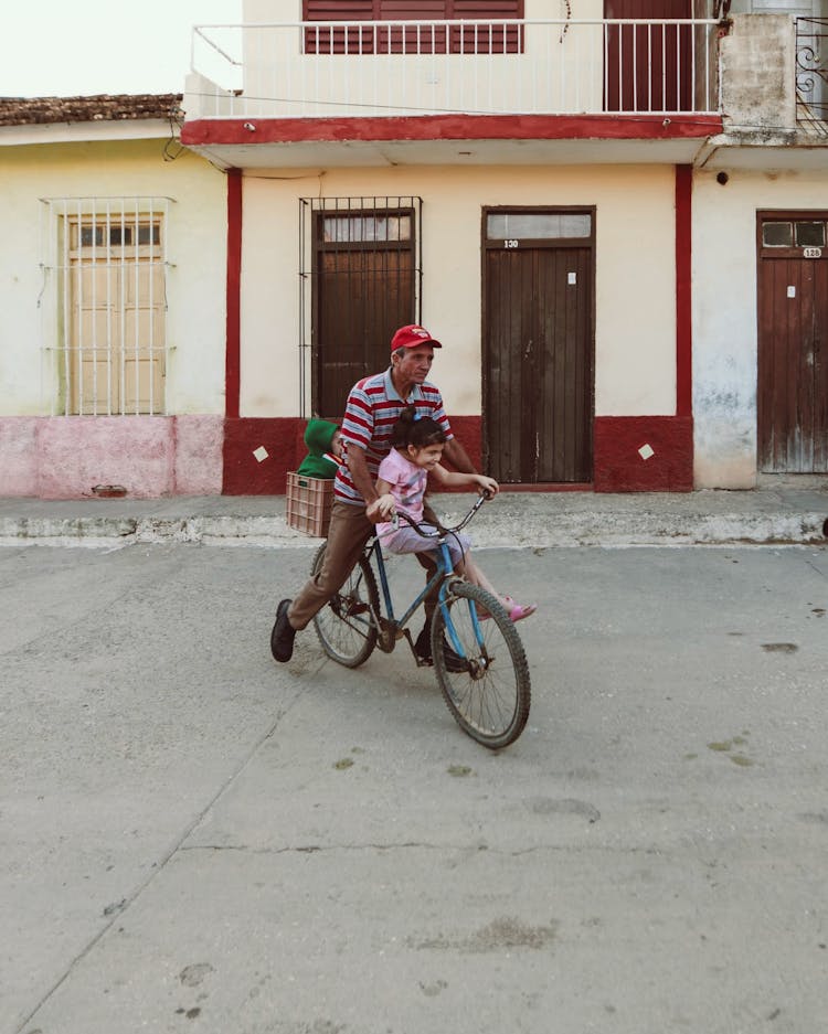 Father With Daughter On Bicycle On Street In Town