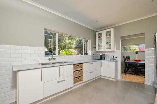 Bright modern kitchen with white cabinetry, overlooking a lush garden in Pretoria, South Africa.