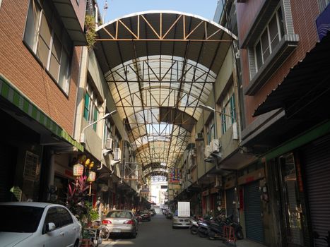 Discover a bustling urban alleyway with shops in Pingtung County, Taiwan, under an intricate roof.