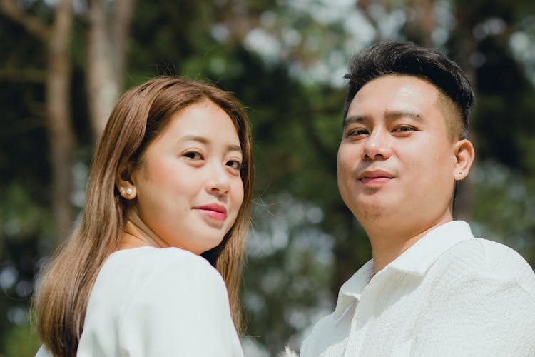 Photo Of A Young Couple Standing Outside In Sunlight And Smiling 