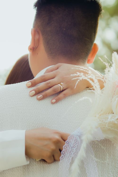 Free Close-up of a couple hugging, showcasing engagement rings and soft florals. Stock Photo