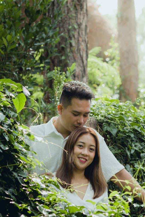 Young Happy Couple Standing Together by a Tree in a Park 