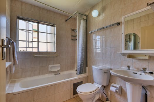 Spacious bathroom with beige tiles, bathtub, and large window, perfect for interior design inspiration.