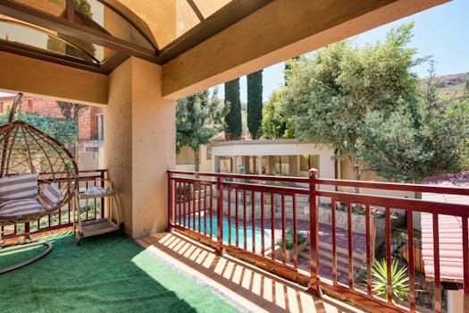 Spacious outdoor terrace overlooking a pool with rattan swing chair, perfect for relaxation.