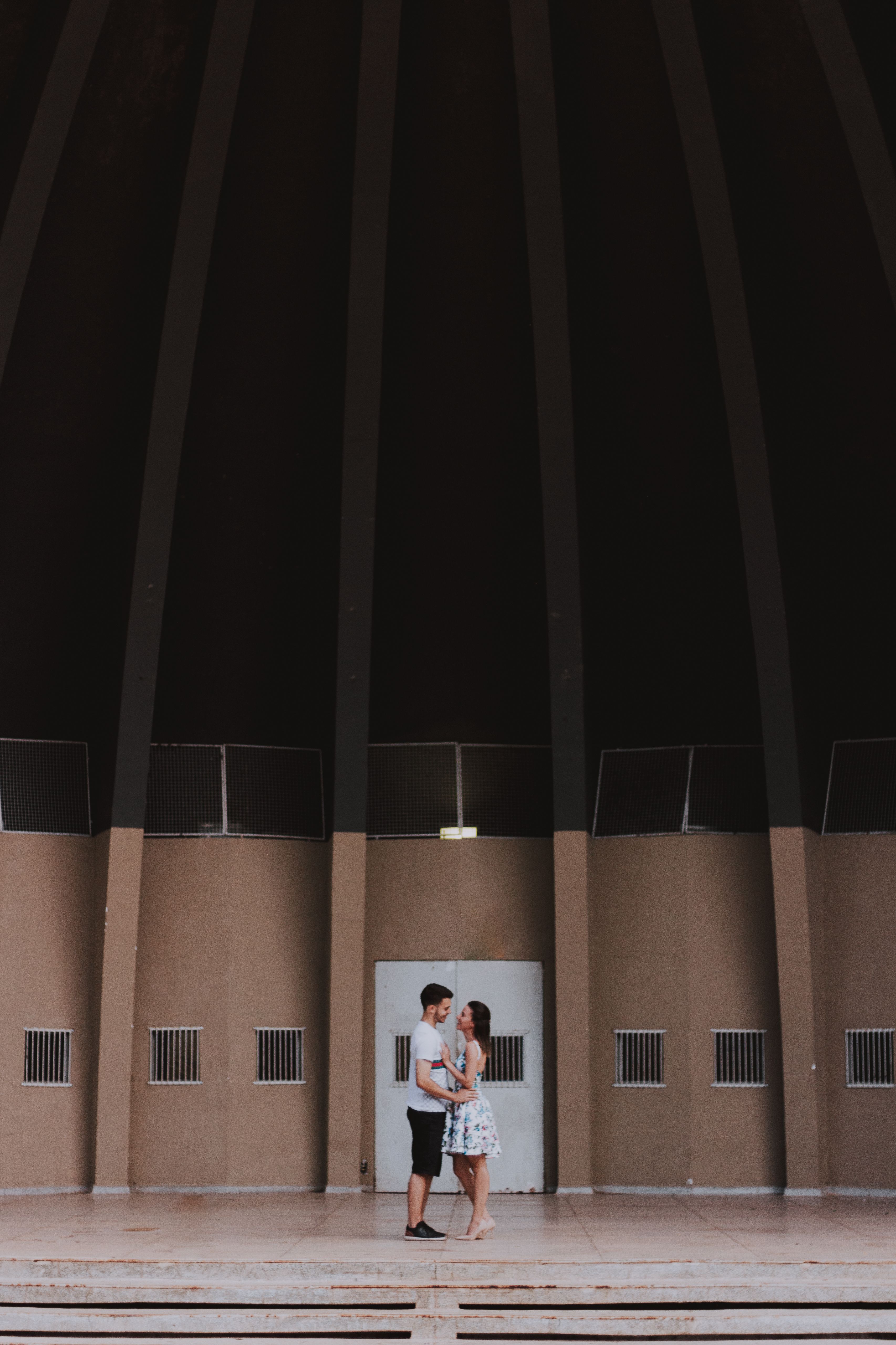 A couple sharing an intimate moment inside a large, modern architectural dome.