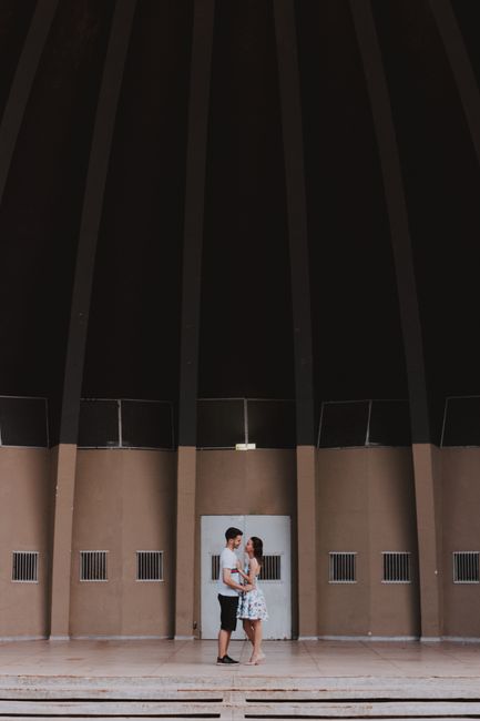 A couple sharing an intimate moment inside a large, modern architectural dome.