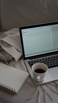 A cozy workspace features a laptop, notebook, and coffee cup on a comfy setup in Ankara, Türkiye.