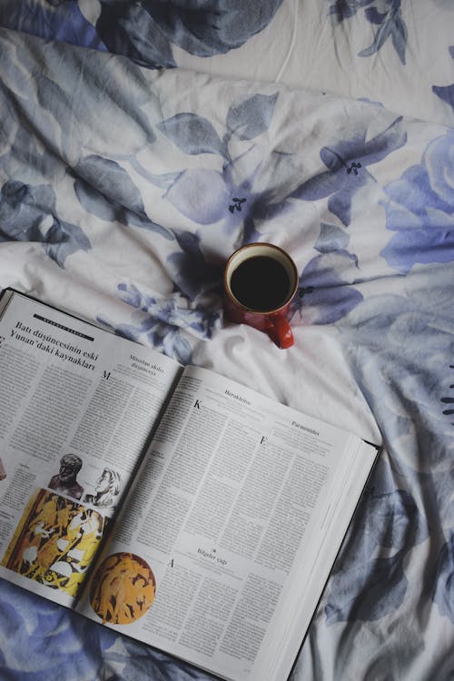 A book and a cup of coffee on a bed