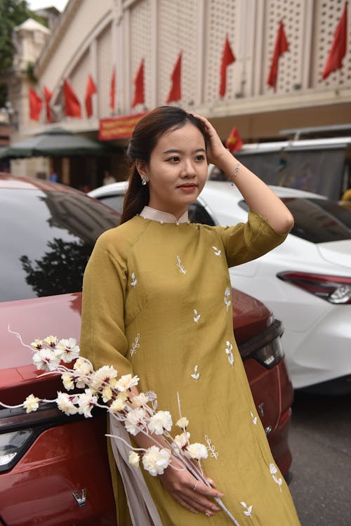 Woman in an Embroidered Green Ao Dai Tunic in the Parking Lot