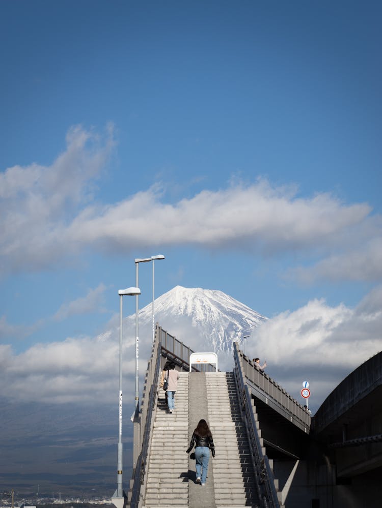 People Walking Up The Stairs With Mount Fuji In The Distance