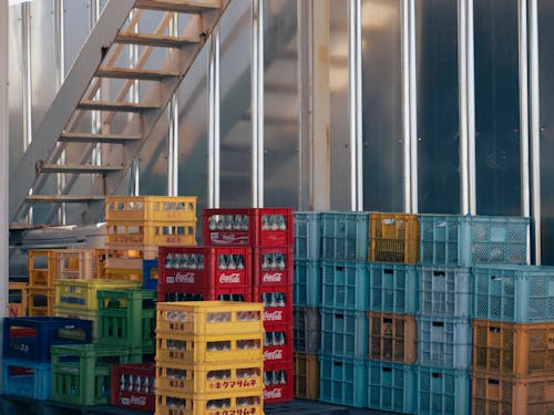 Free A collection of colorful crates stacked beside an industrial staircase outdoors. Stock Photo