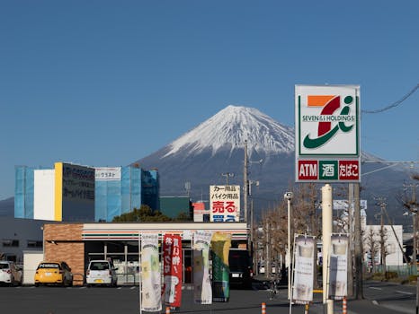 Mount Fuji visible behind a 7-Eleven store sign in Shizuoka, Japan.