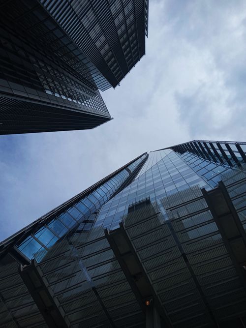 Free Low angle view of modern skyscrapers showcasing glass architecture against a cloudy sky. Stock Photo