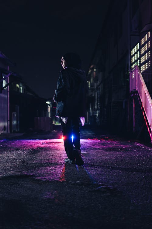 Woman in Jacket and Headscarf on City Street at Night