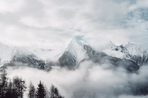 Snow Covered Mountain Range Among Clouds and Steam