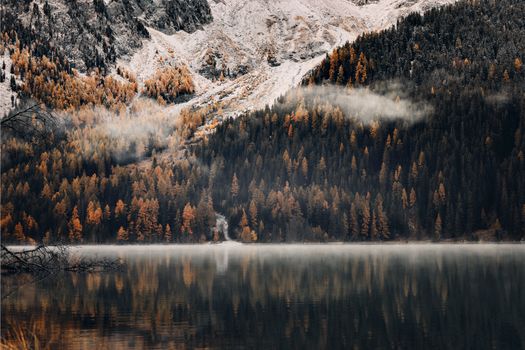 Tranquil winter landscape with snow-covered mountains and a reflecting lake.