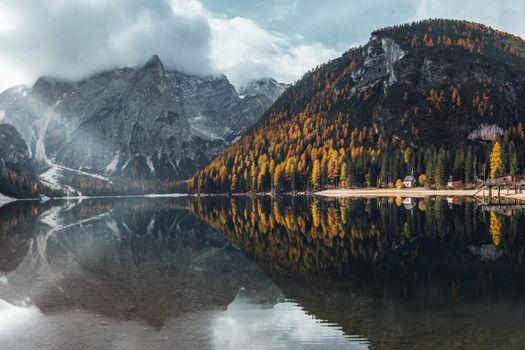 Breathtaking view of Lago di Braies with mountains and autumn trees reflecting in the water.