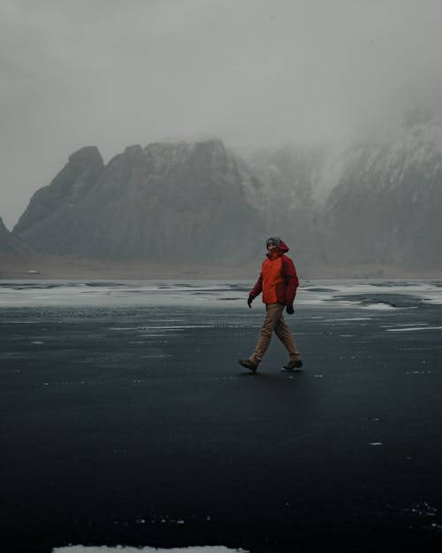 Man Walking on Black Ice on a Frozen Lake in the Mountains