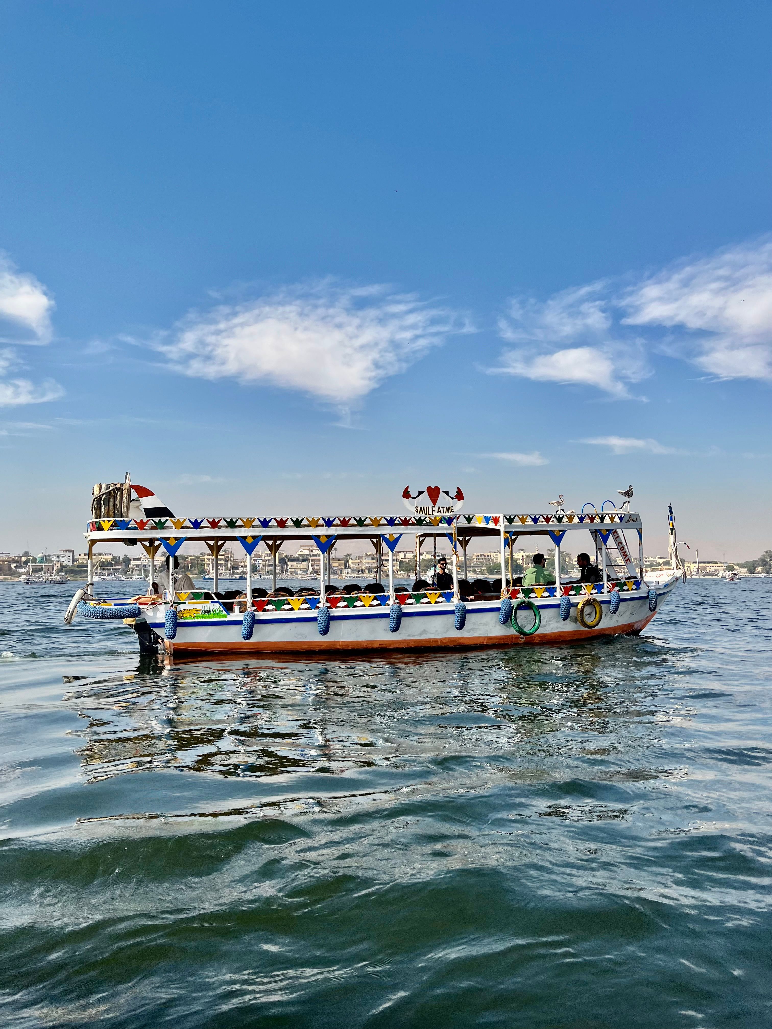 A colorful traditional boat sailing on the Nile River under a clear sky in Egypt.