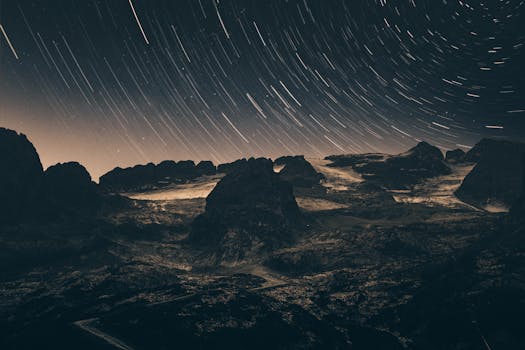 Explore the captivating night sky with star trails over a rugged rocky landscape.