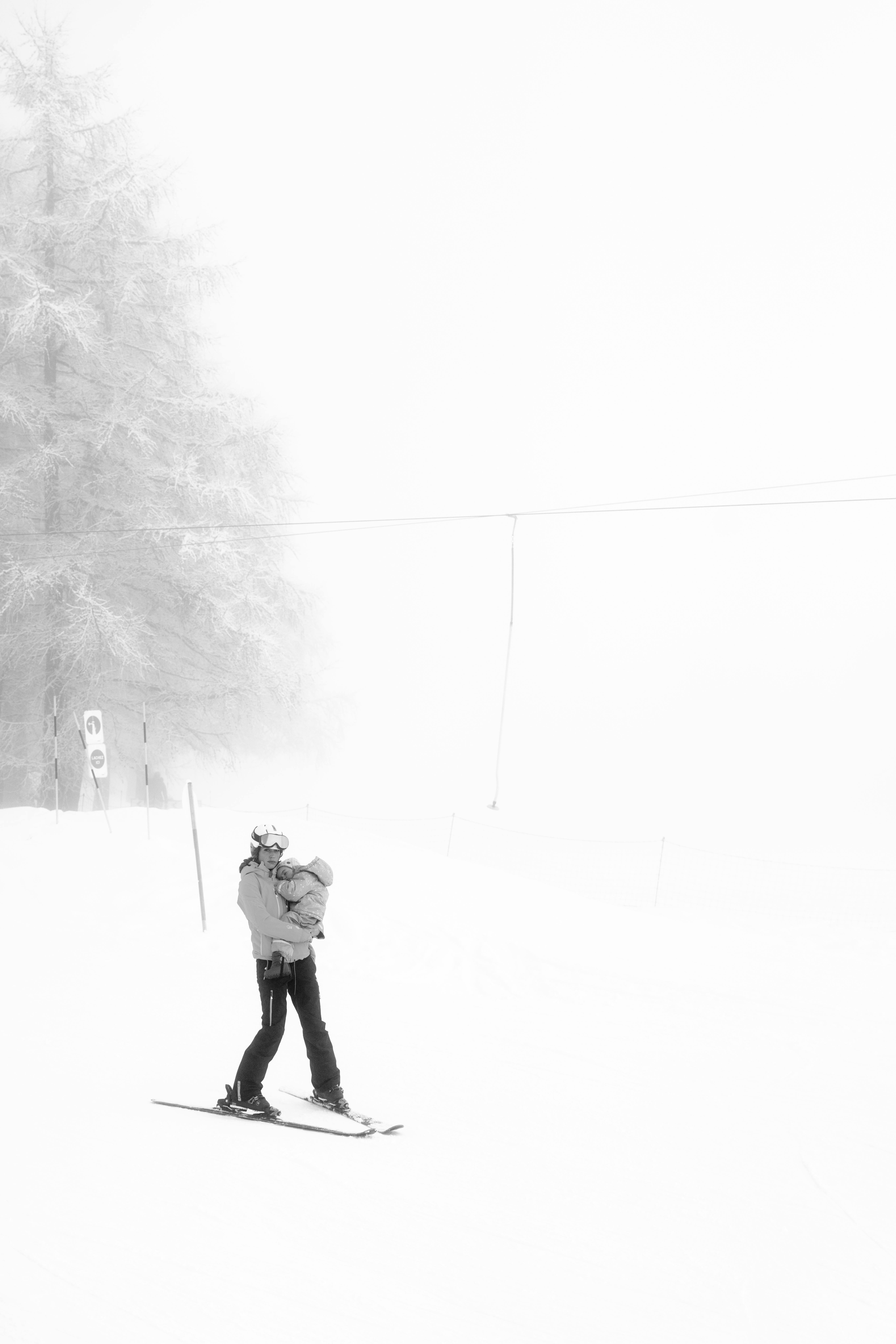 Prescription Goggle Inserts - A parent holding a child skiing in a foggy winter scene with trees in the background.