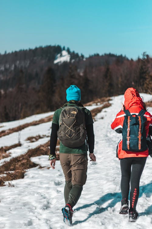 Two People Walking On Snow Trail