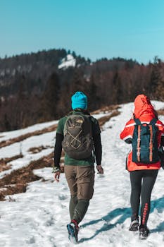 两名成年人在雪山步道上徒步，享受冬季户外冒险