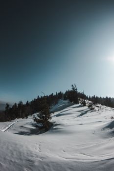 Peaceful snow-covered mountain landscape captured at dawn with clear sky.