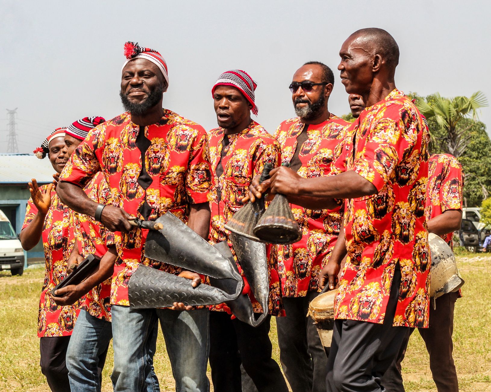 Group of African musicians in vibrant traditional attire playing instruments outdoors, showcasing cultural heritage.