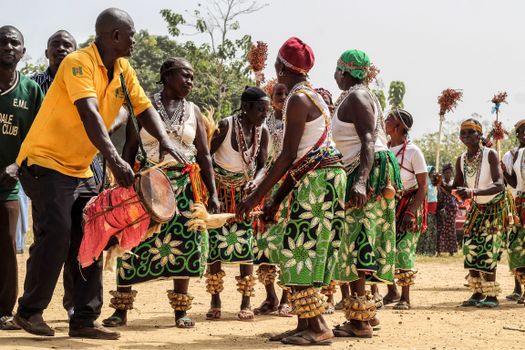 Colorful traditional dance group performing outdoors with drums and cultural attire.