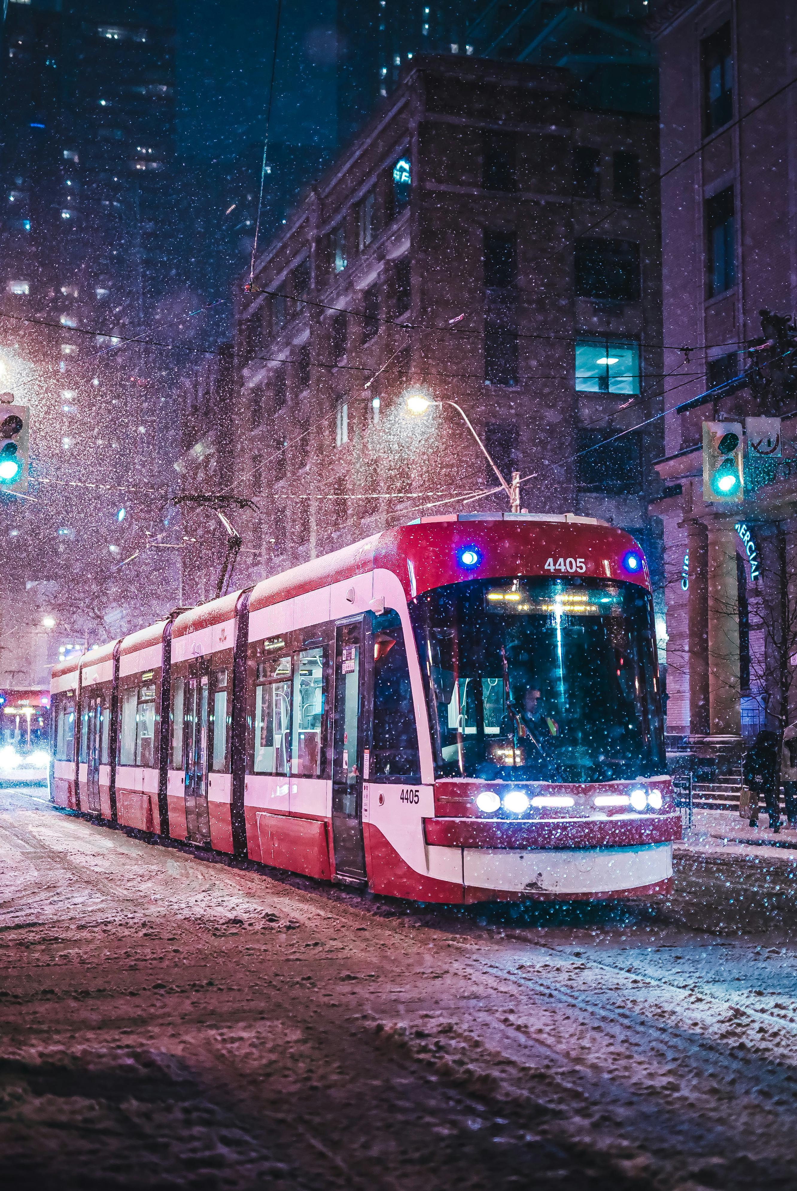 City tram moves through snowy winter night, capturing urban transport under streetlights.