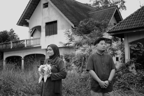 Woman in Hijab Standing with Flowers and Man in Shirt in Black and White