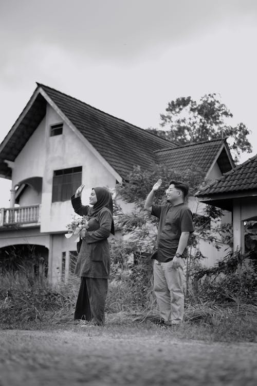 Woman and Man Standing near House and Waving