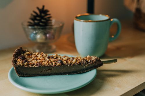 Free A slice of chocolate nut tart on a plate beside a blue mug, perfect for a cozy treat. Stock Photo