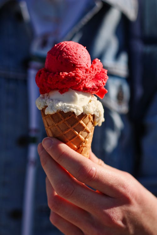 Person Holding Ice Cream Cone With Strawberry Ice Cream