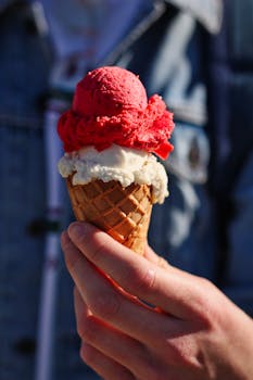 手拿美味的甜筒冰淇淋，华夫饼甜筒里插着红白相间的鲜艳勺子