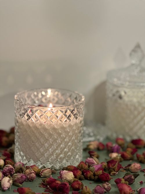 Free A cozy scene of a lit candle in a glass holder surrounded by dried rose petals, perfect for interior design. Stock Photo
