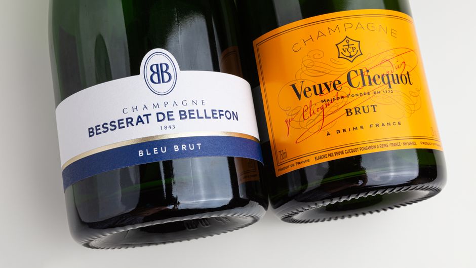 Close-up of Besserat de Bellefon and Veuve Clicquot champagne bottles on a white background.