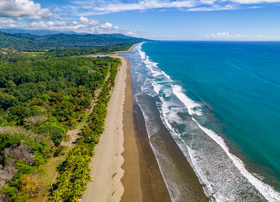A breathtaking aerial view of the coastline at Puntarenas, Costa Rica, showcasing pristine beaches and lush greenery.