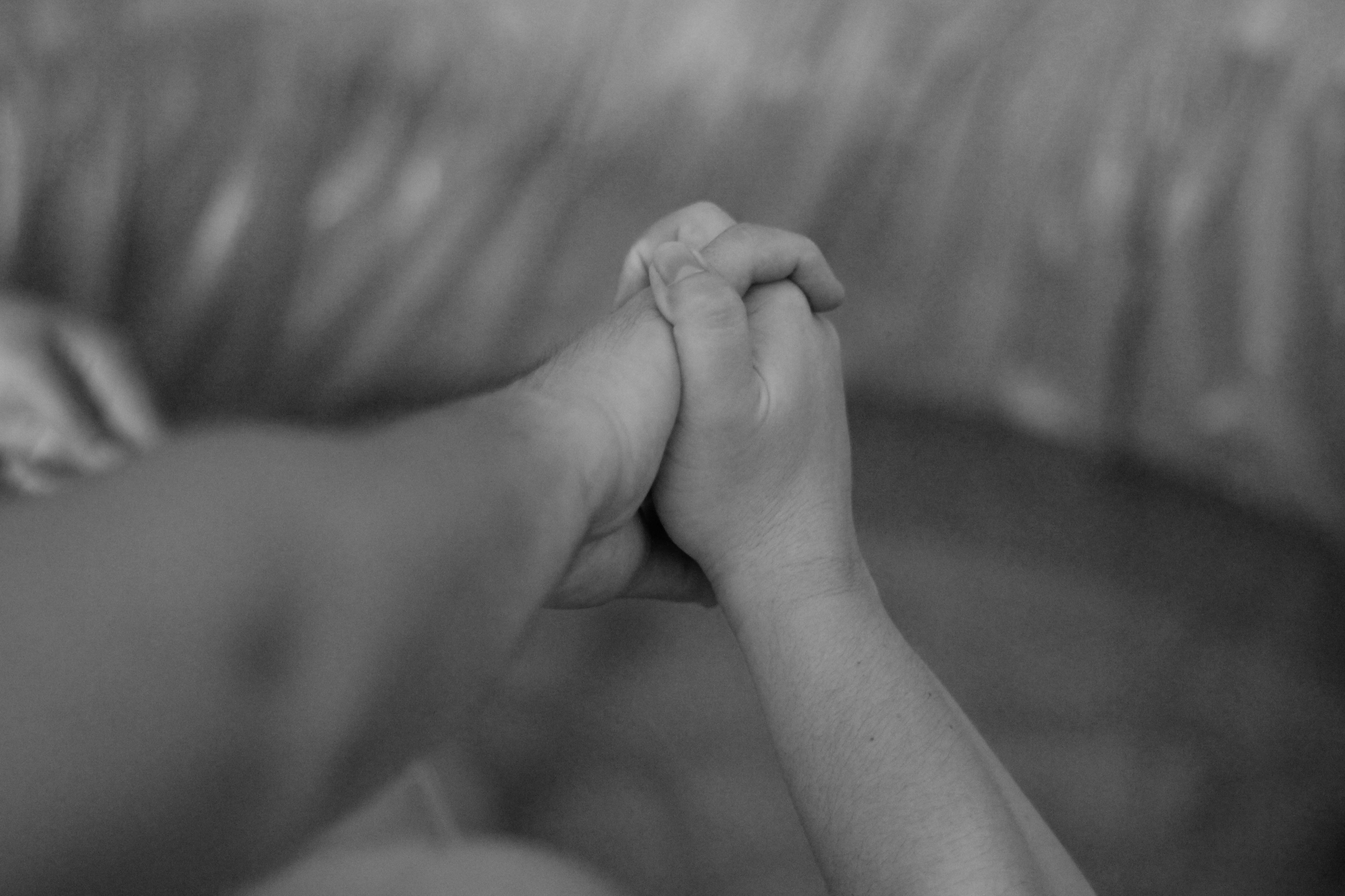 A touching black and white photo of two hands holding, symbolizing connection and support.