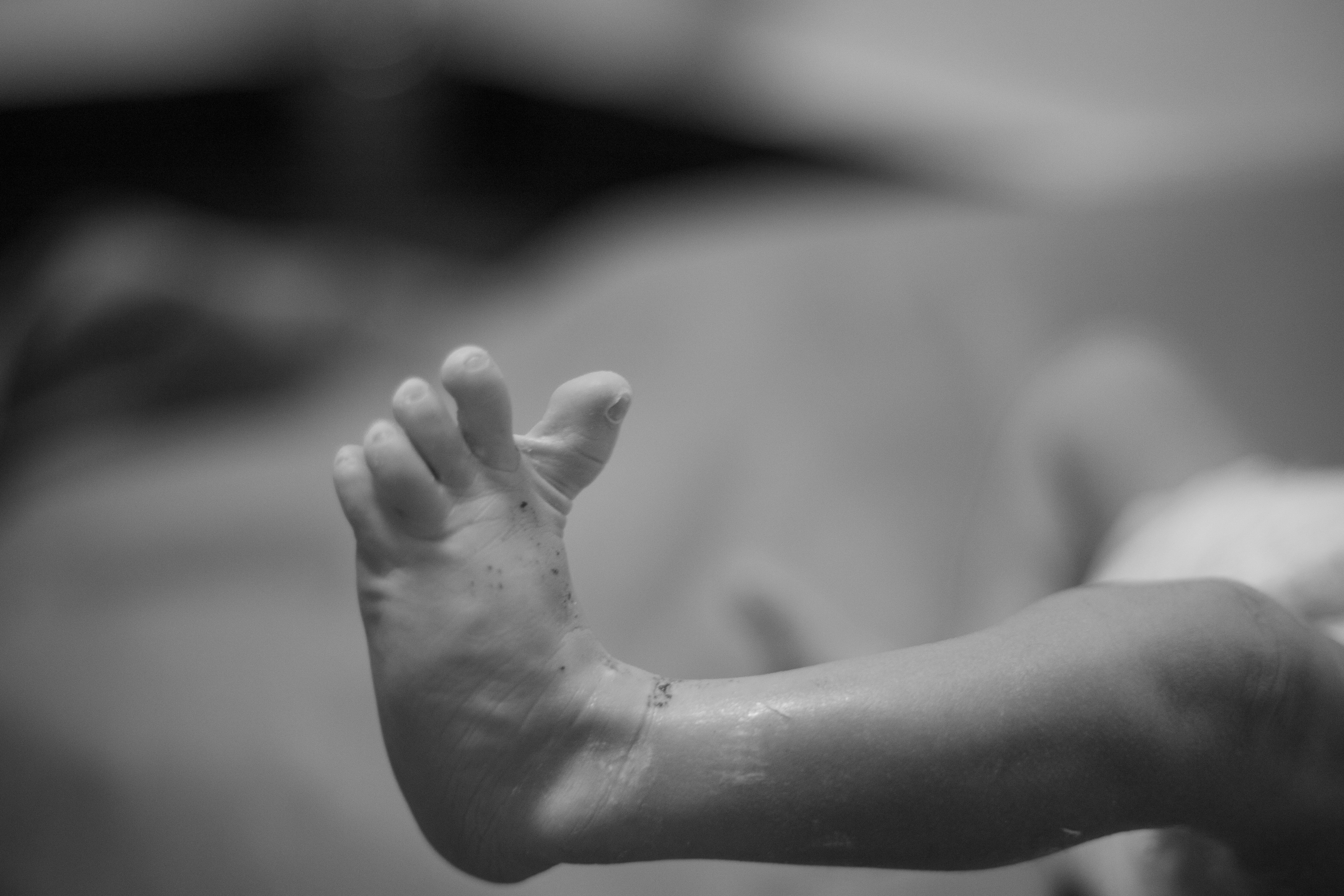 Artistic black and white close-up of a newborn's foot, emphasizing delicate details.
