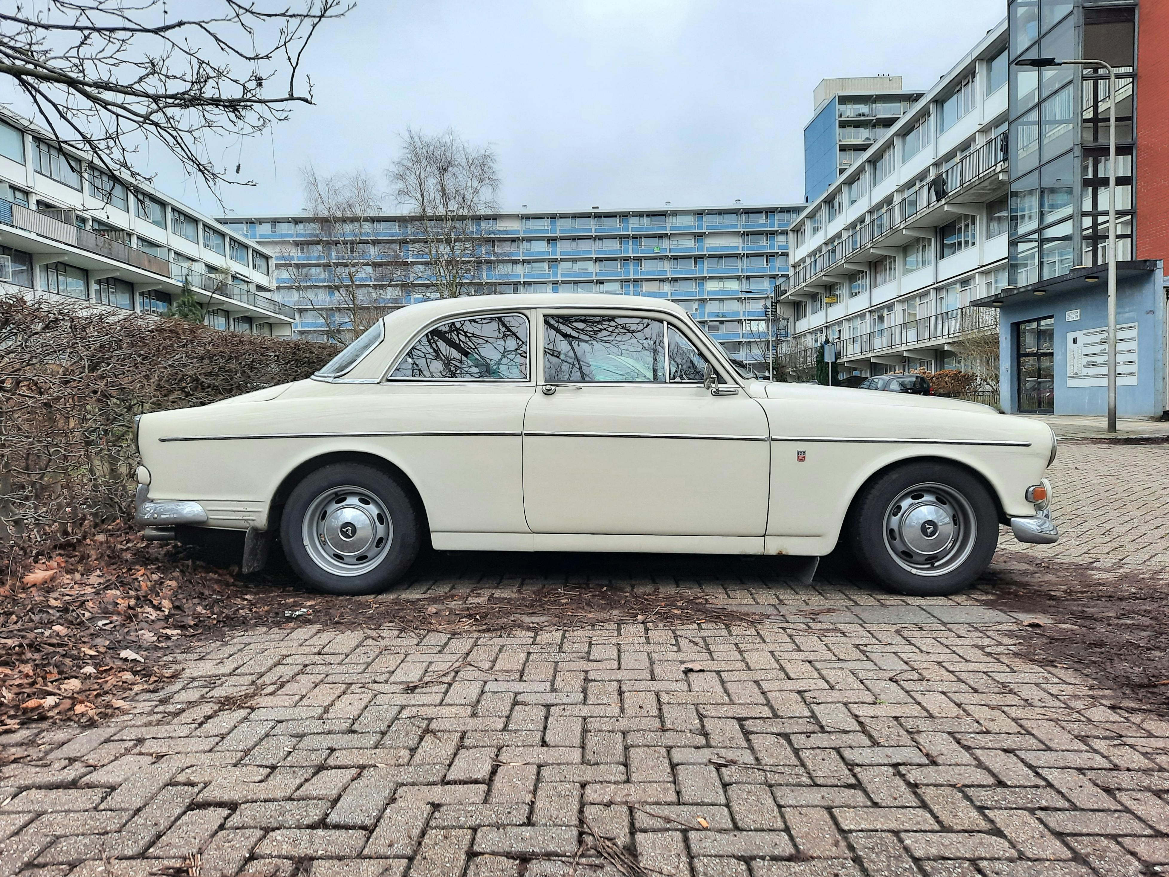 a vintage volvo amazon on a parking lot in city