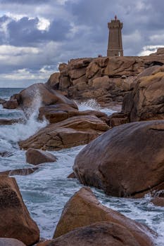 Waves crash against the rocks near Men Ruz Lighthouse in Perros-Guirec, Bretagne, France.