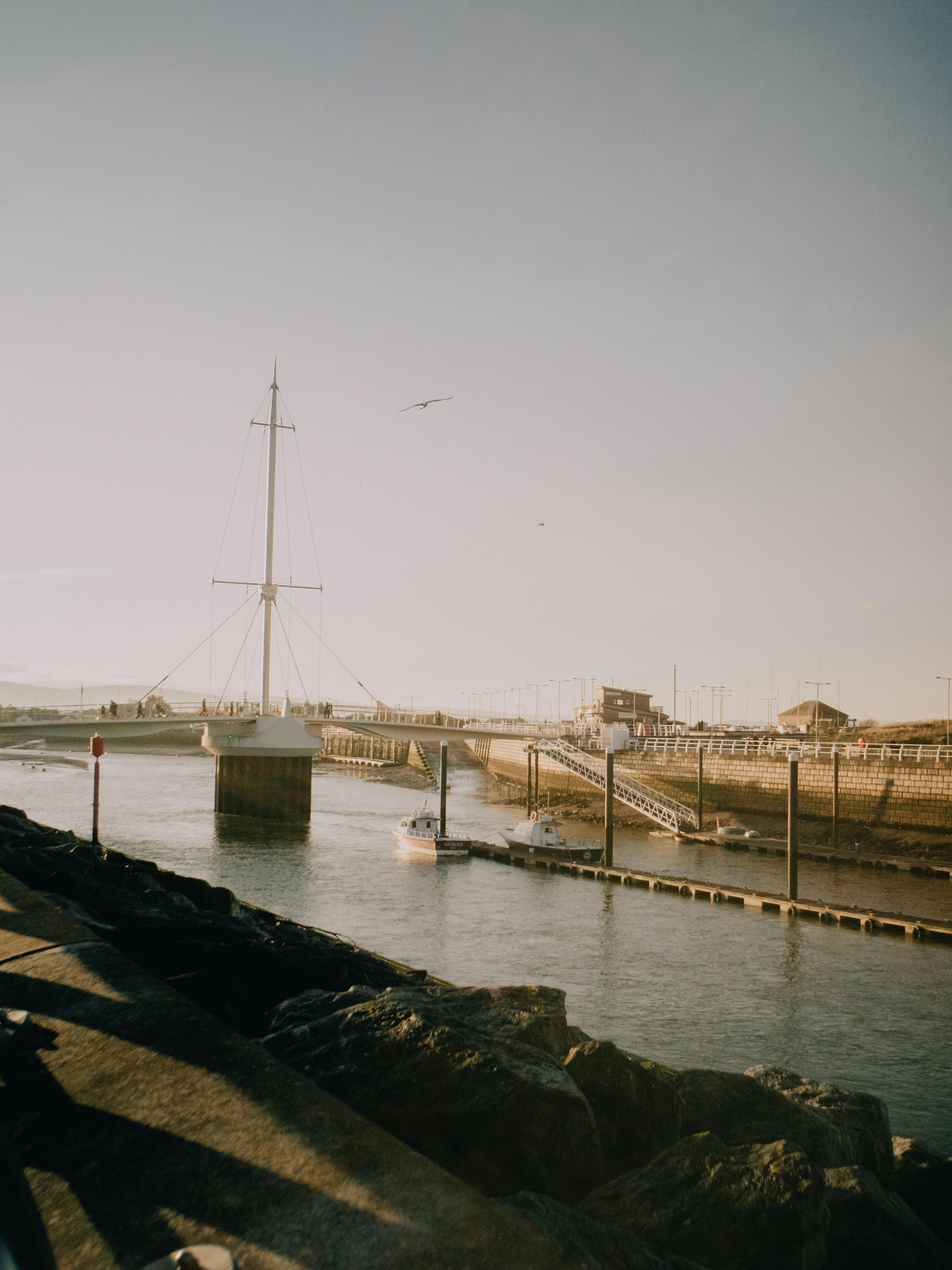 Tranquil harbor scene in Rhyl, Wales, showcasing a scenic view of sailboats and the water under sunlight.
