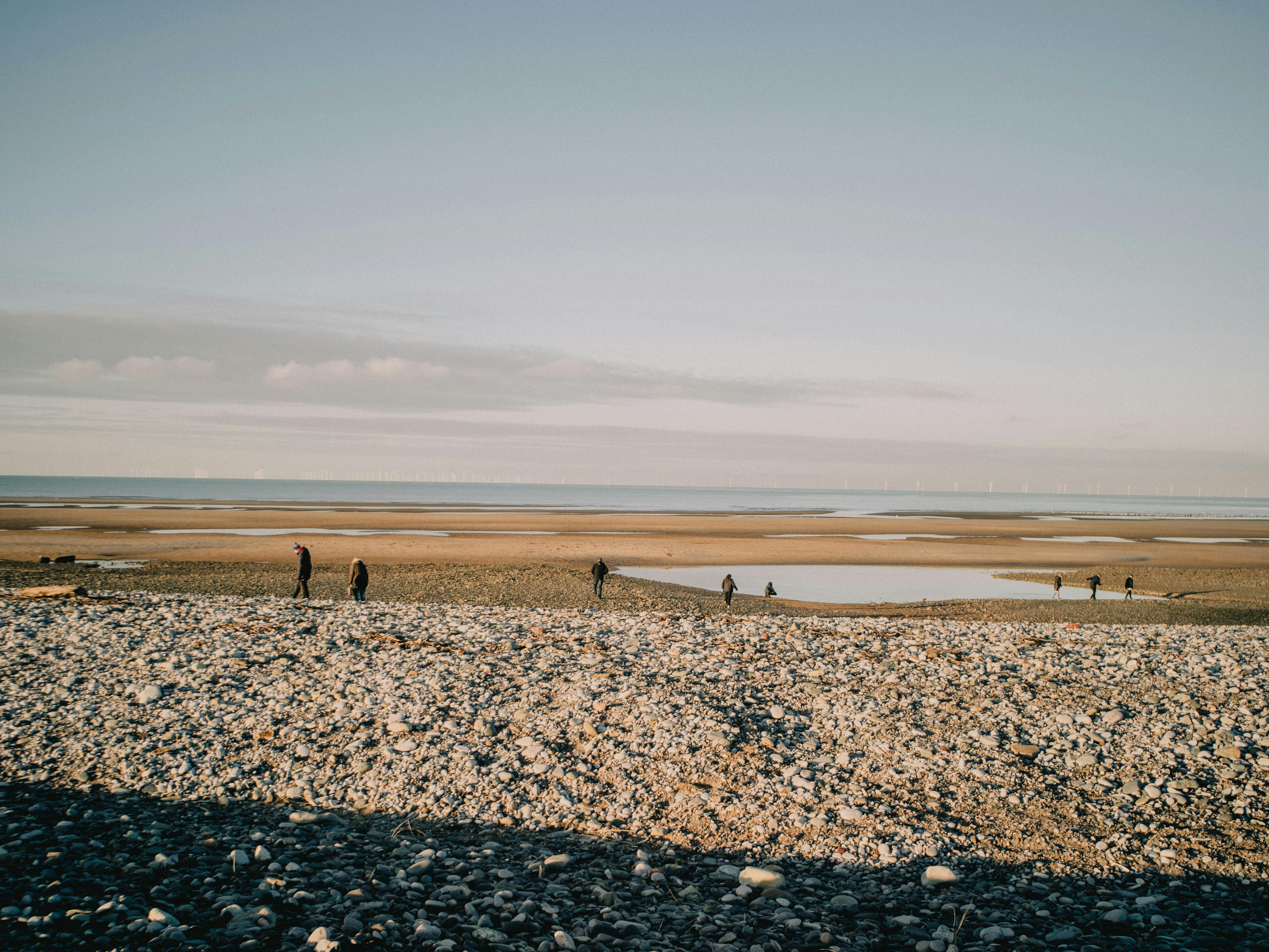 Peaceful beach scene in Rhyl, Wales featuring people walking on a sunny day.