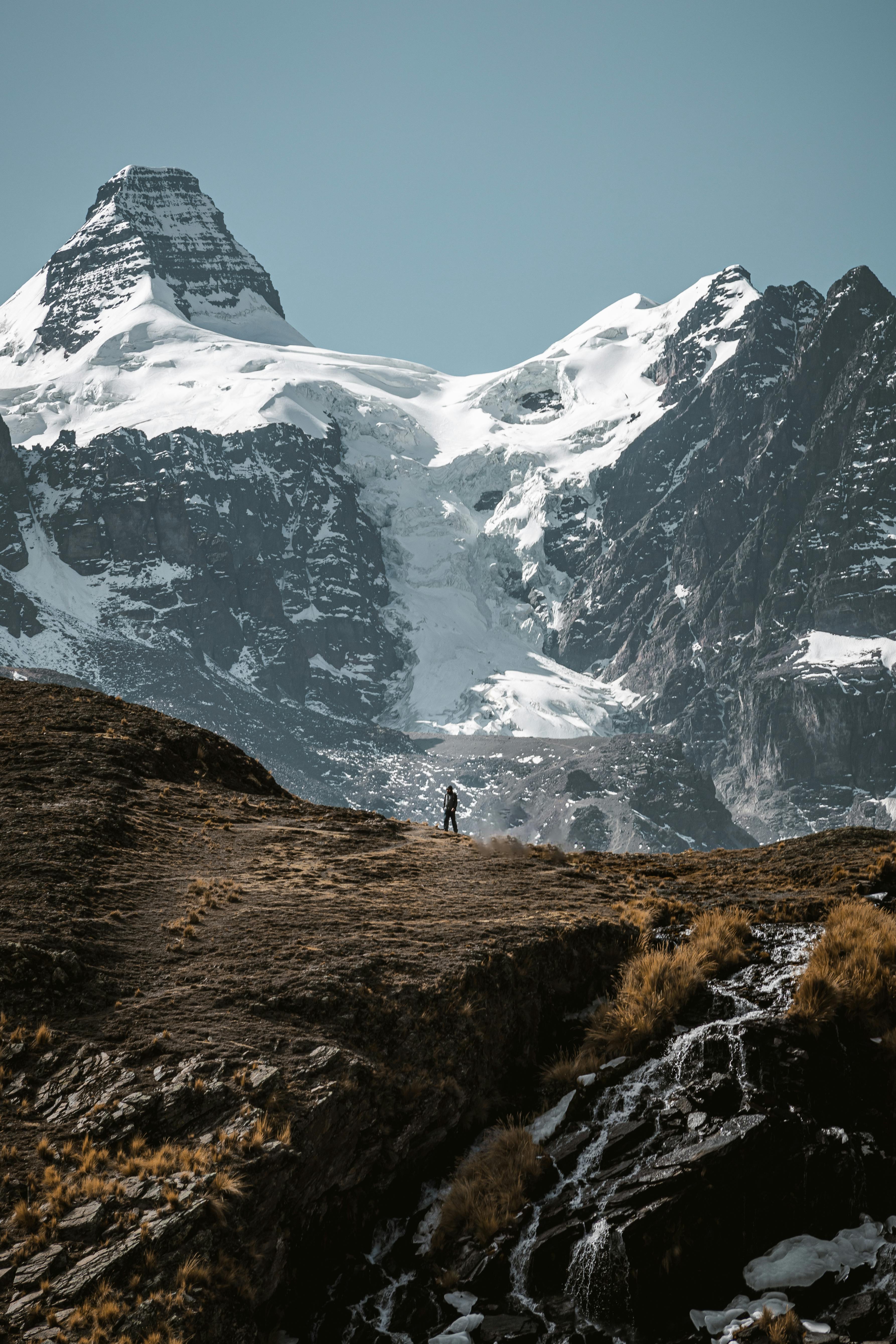 A lone mountaineer stands before the majestic snowcapped Condoriri peaks in Bolivia.