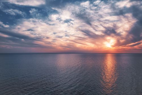 Free A tranquil ocean scene captured during a dramatic sunset, showcasing vibrant clouds and serene waters. Stock Photo