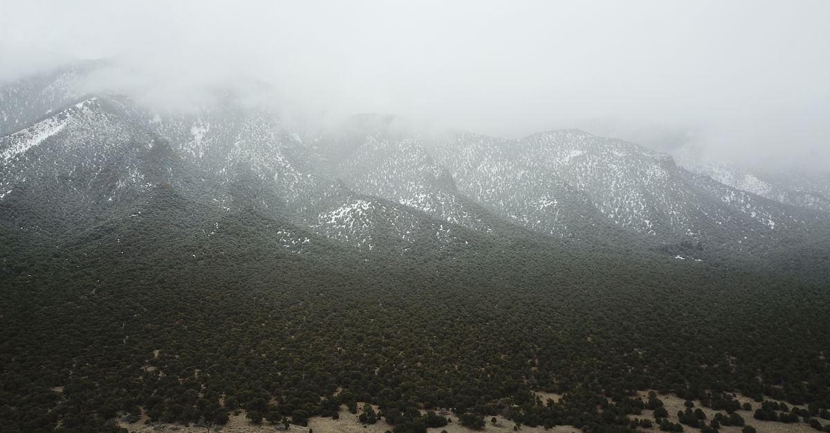 Aerial view of misty mountains and dense forest creating a dramatic nature scene.