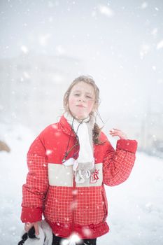 Young girl in red jacket enjoying snowfall in Amman, Jordan during winter.