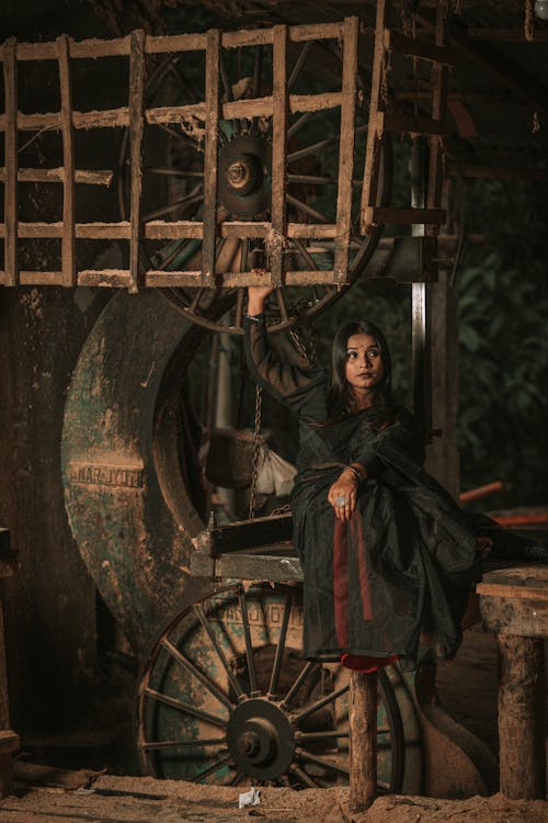 Woman in a Dark Dress Sitting in a Room with Vintage Machinery 